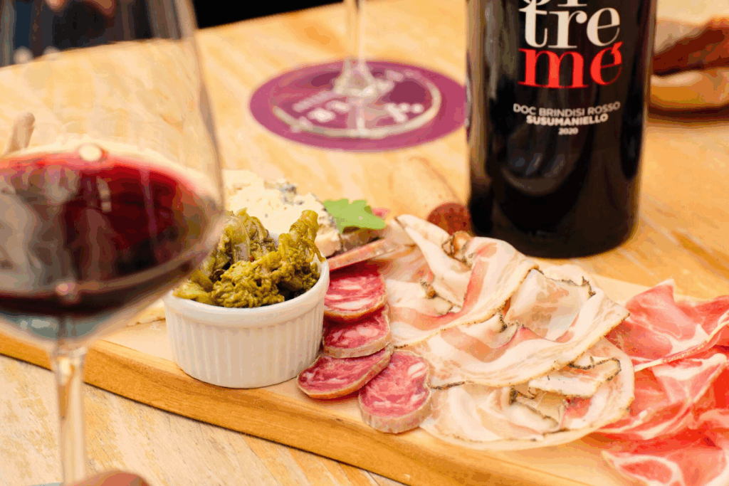 Tagliere di formaggi e salumi con bicchiere di vino rosso